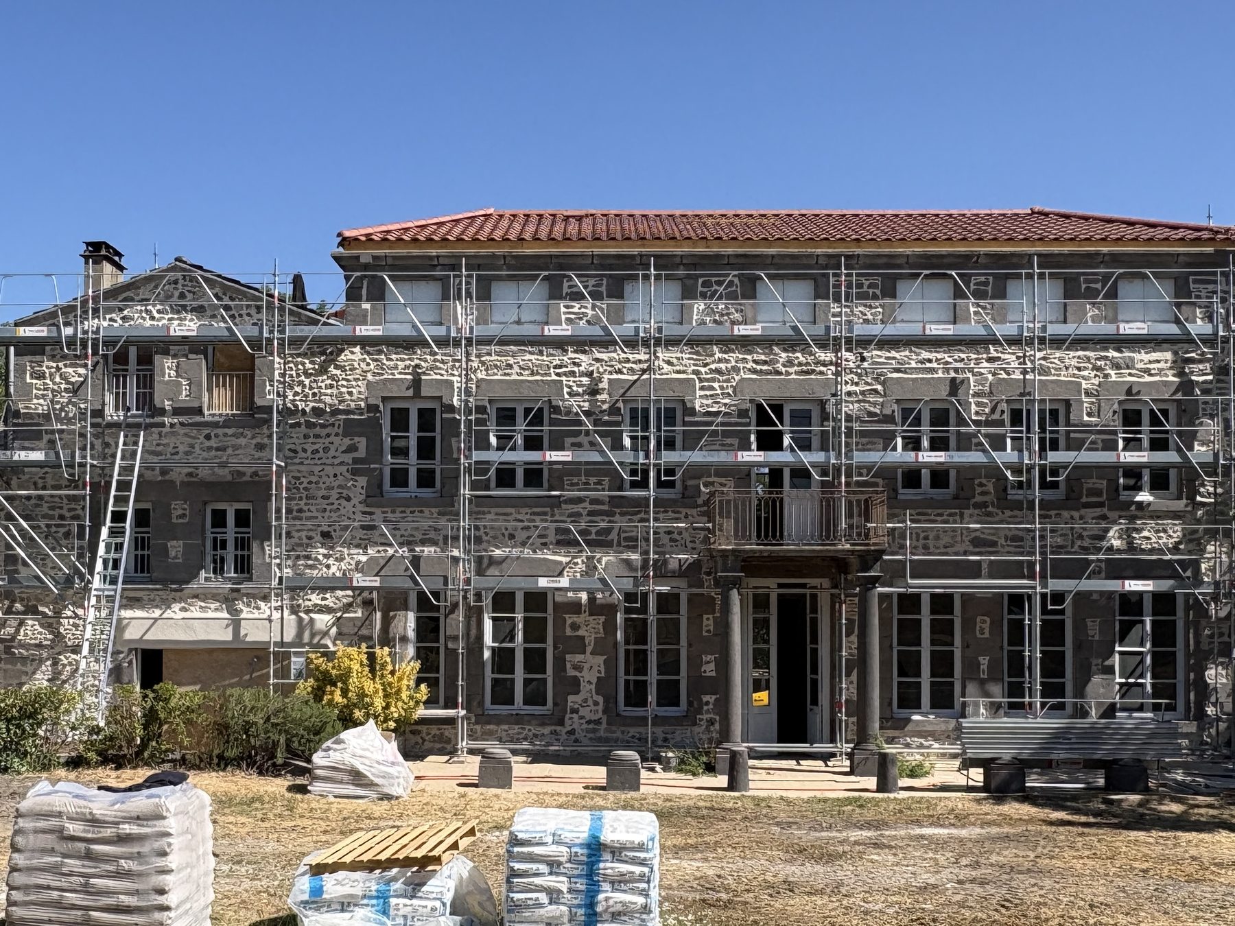 Stone façade of a manor house under scaffolding, being renovated by JR Bâtiment